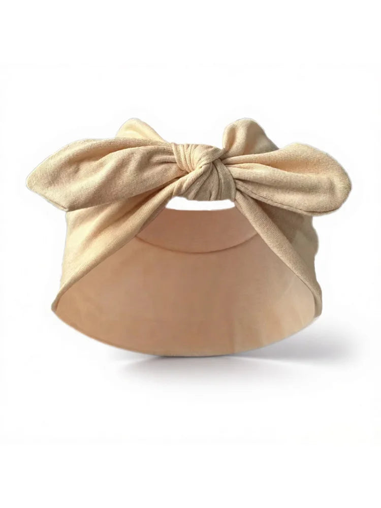 Un bandeau élastique beige noué en nœud, présenté sur fond blanc.