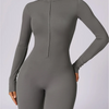 Model trägt einen eng anliegenden, langärmeligen, grauen Zip-Jumpsuit für Yoga.