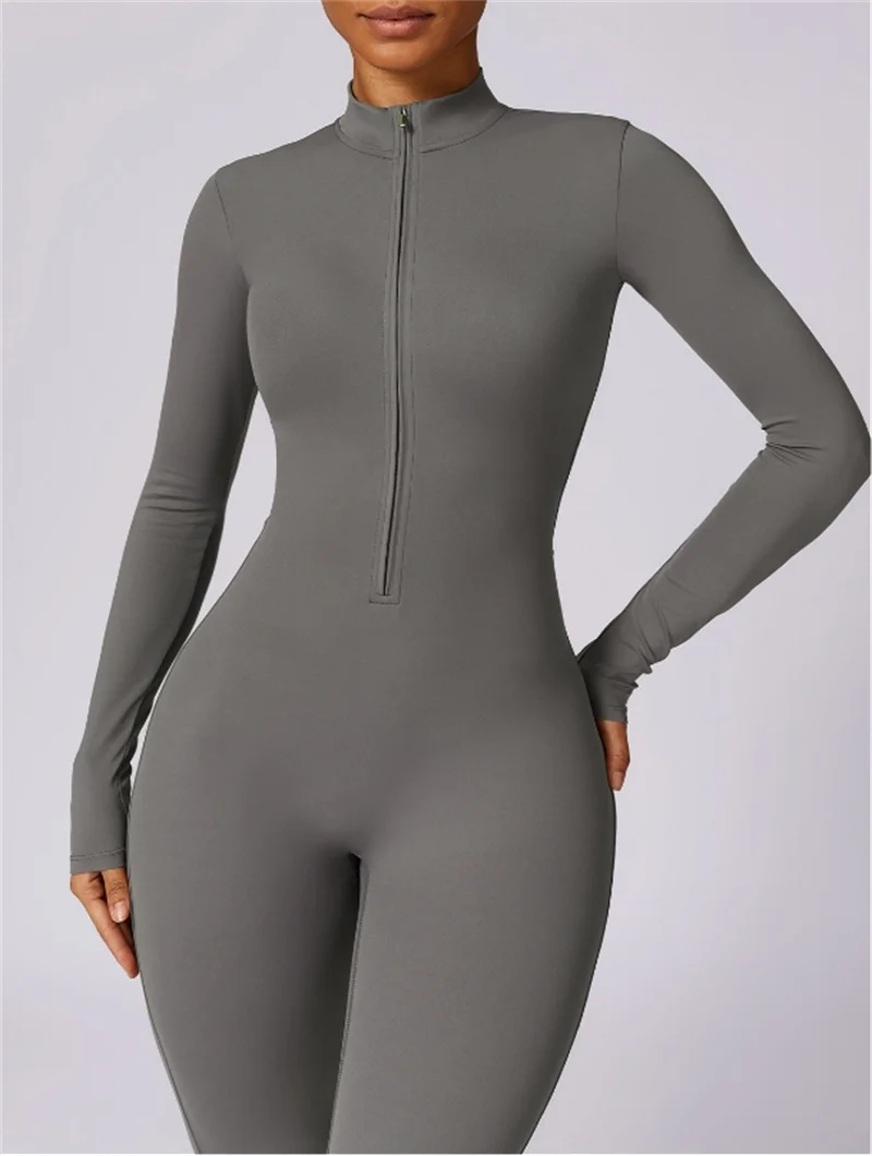Model trägt einen eng anliegenden, langärmeligen, grauen Zip-Jumpsuit für Yoga.