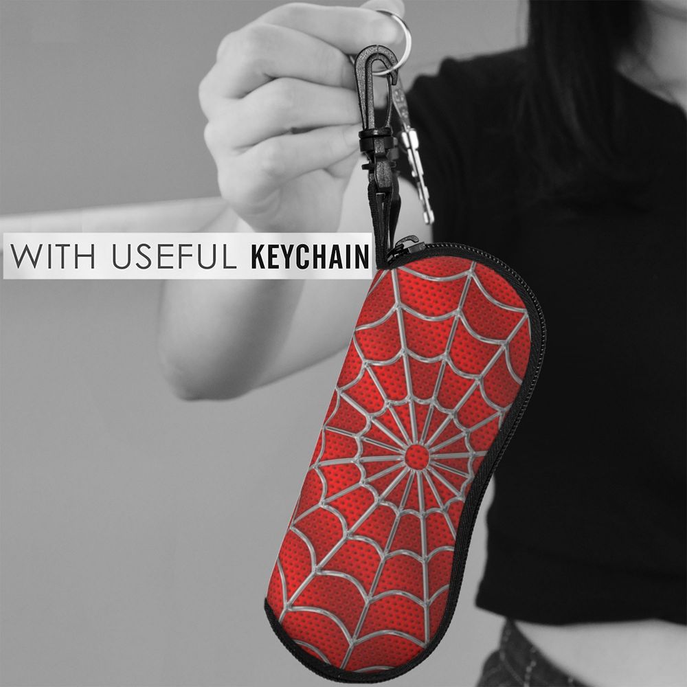 A red spider web patterned eyeglass pouch attached to a keychain, held by a person.