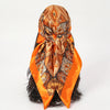 An elegant orange satin square scarf tied around dark hair.