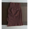 Un short de yoga sans coutures, taille haute et marron foncé, posé sur une surface texturée.