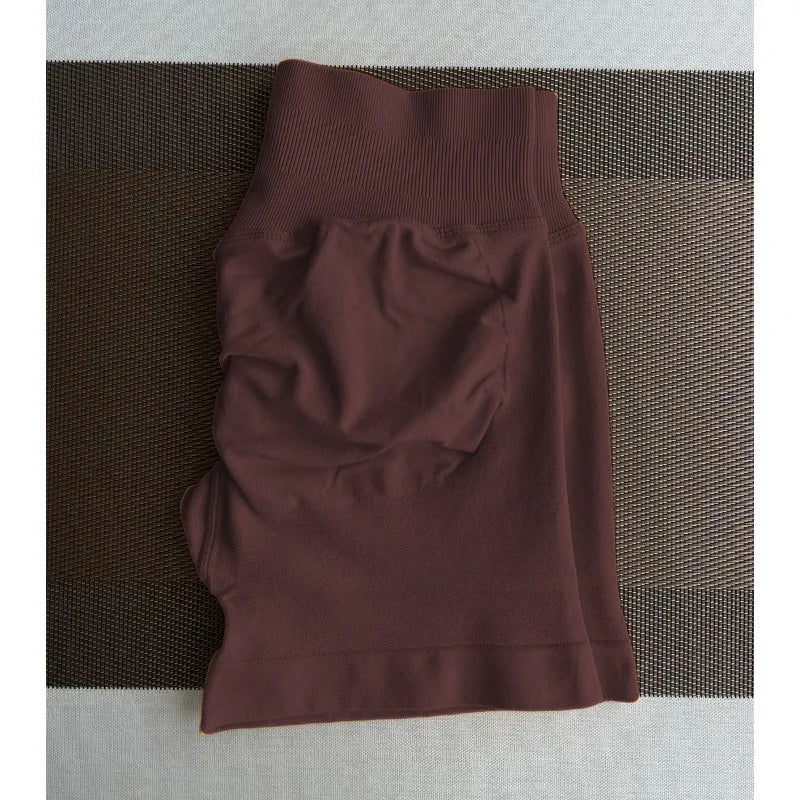 Un short de yoga sans coutures, taille haute et marron foncé, posé sur une surface texturée.