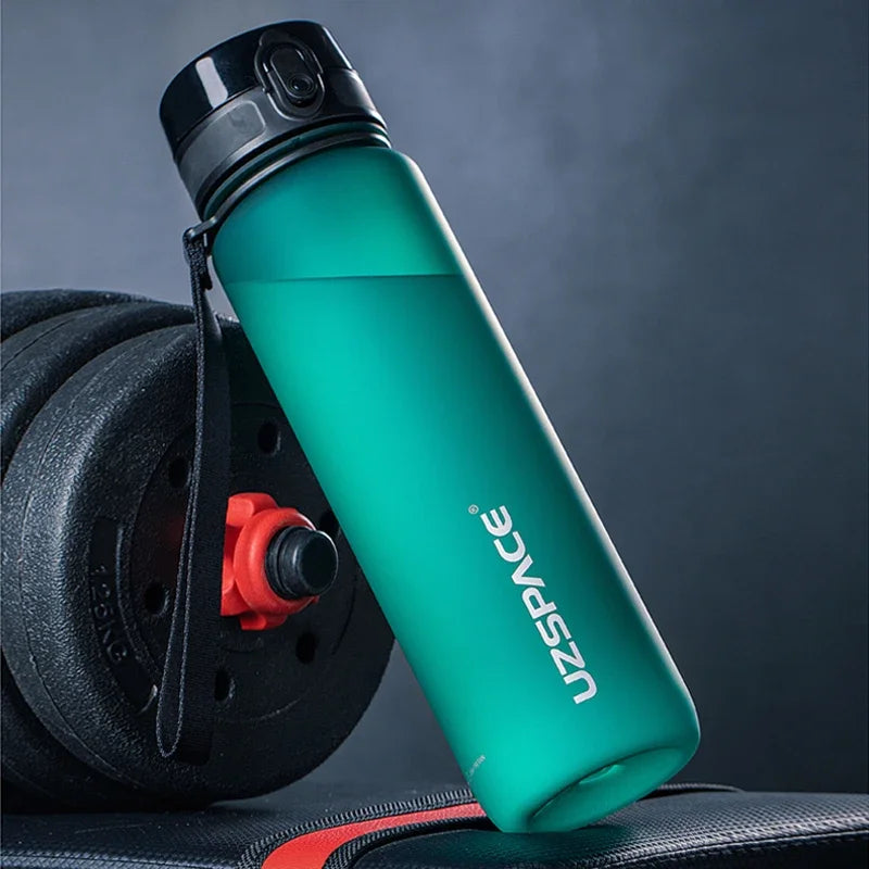 Türkis-Sportflasche mit schwarzem Deckel und Seil neben einem schwarzen Trainingsrad.