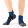 A pair of navy blue performance running socks with yellow accents shown on a person's foot.