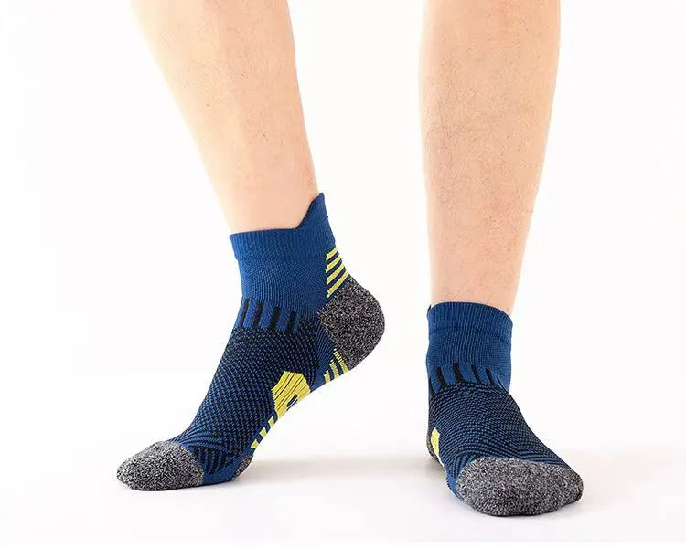 A pair of navy blue performance running socks with yellow accents shown on a person's foot.
