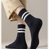 A close-up of black striped men's socks worn on a foot, paired with light tan trousers.