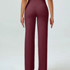A woman wearing maroon high waisted yoga pants and a light top.
