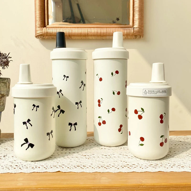 Un ensemble de gourdes isolées blanches avec couvercles à paille décorés de petites illustrations de cerises rouges.