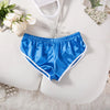 Helle blaue Satin-Jogginghose, flach auf weißer Oberfläche mit Blumenakzenten.