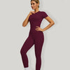 Eine Frau modelliert ein sportliches Yoga-Set in tiefem Bordeauxrot mit kurzem Oberteil und Leggings.