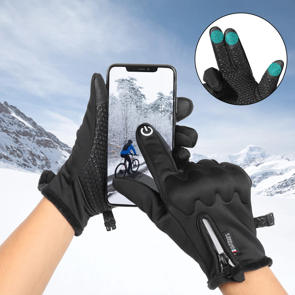 Black tactical gloves with a touchscreen feature are shown being worn outdoors in a snowy mountain landscape.