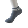 Gray non-slip grip socks with a ribbed cuff and white stripes worn on a model's foot.