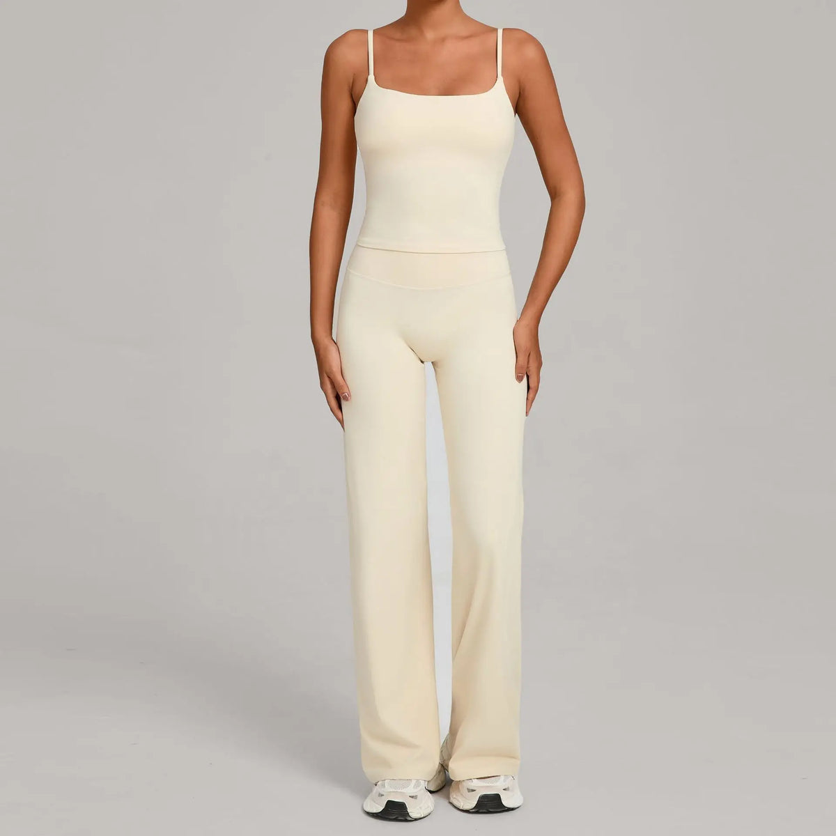 A woman wearing a cream-colored high-waist yoga and fitness tracksuit set.