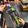 A hand holds an insulated sports water bottle with a leakproof straw, showing the clear plastic bottle and yellow cap.