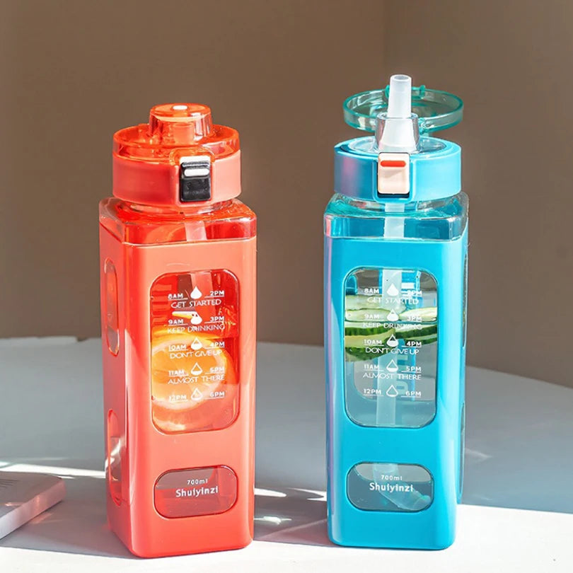 Klare blaue portable Sportflasche mit Strohhalm und orangefarbener Kappe auf weißem Untergrund.