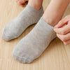 Une personne met une paire de chaussettes invisibles anti-dérapantes gris clair.