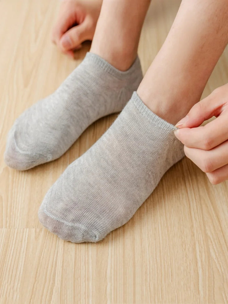 Une personne met une paire de chaussettes invisibles anti-dérapantes gris clair.