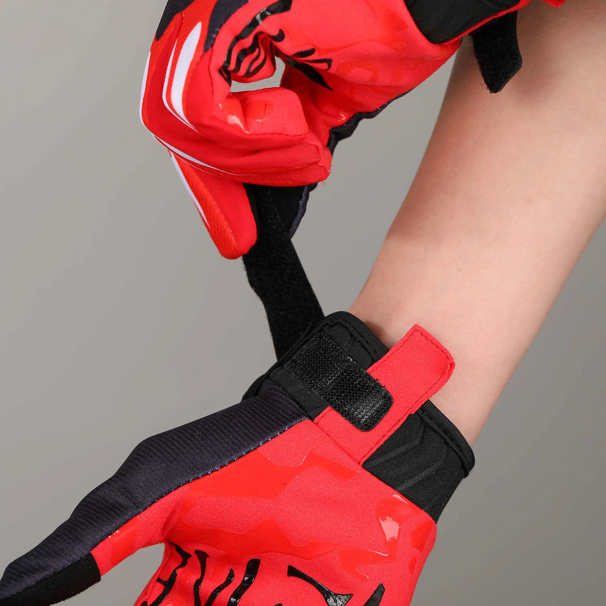 Close-up of a person wearing red and black cycling riding gloves on their hand and wrist.