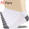 A stack of ten pairs of white and gray ankle socks displayed on a person's leg.