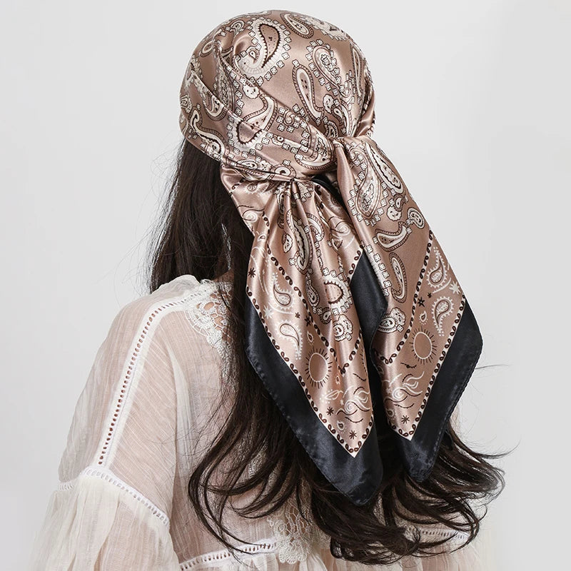 A woman wearing a silk paisley shawl scarf with gold and black patterns, shown from the back.