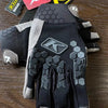 Une paire de gants de moto tactiques noirs avec des accents gris et une texture de prise sont présentés sur une surface en bo