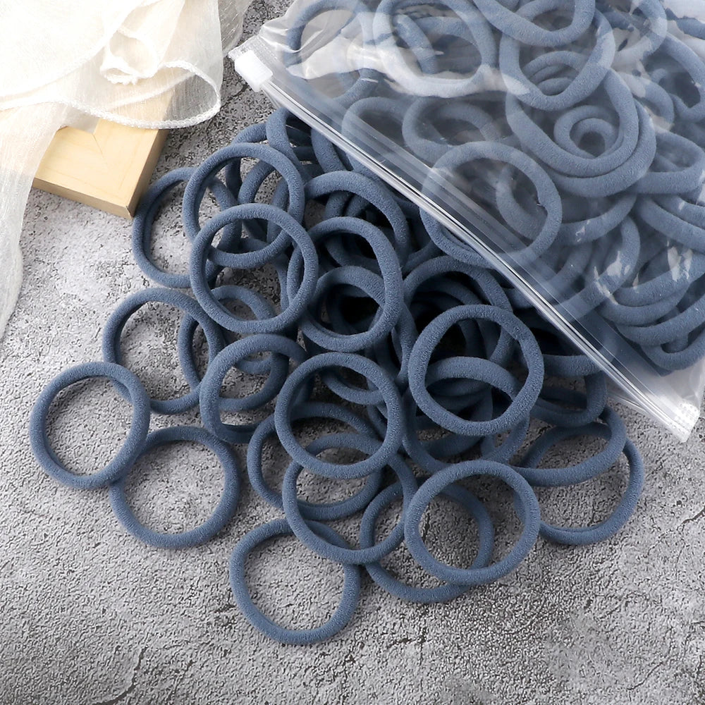 A pile of dark blue elastic hair bands in various sizes and colors, some packaged in clear plastic.