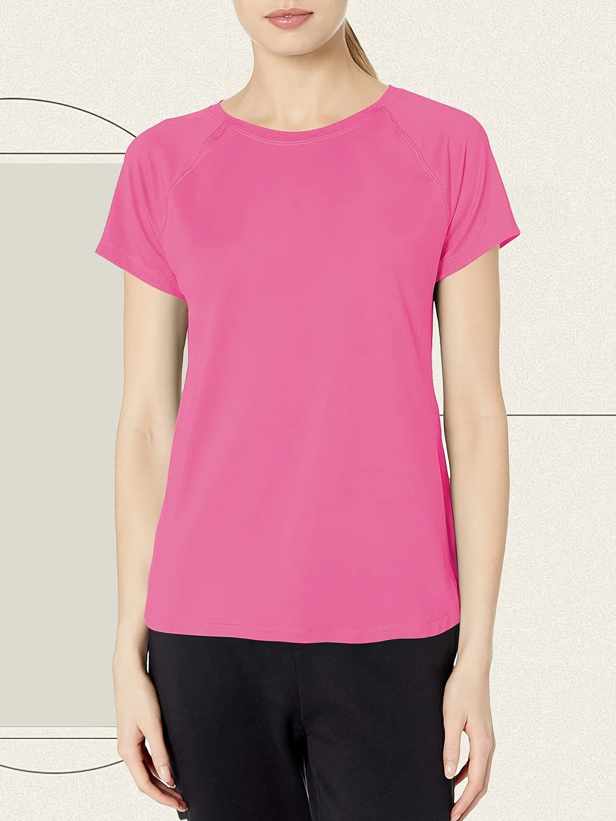 A woman wearing a bright pink quick dry moisture-wicking gym t-shirt and black pants.
