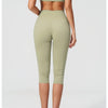 A woman models a light olive green women's premium fitness tracksuit consisting of a cropped top and fitted pants.