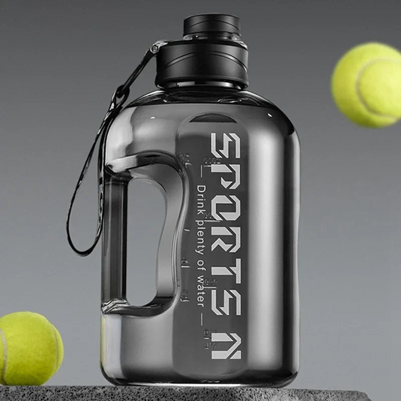 Klare Sportflasche mit schwarzem Verschluss und Drahtschlaufe neben einem Tennisball.