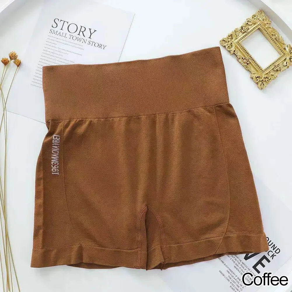 Un par de shorts deportivos sin costuras marrones para mujer, extendidos sobre una superficie blanca.