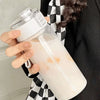 A hand holds a large capacity transparent sports water bottle filled with a milky liquid.