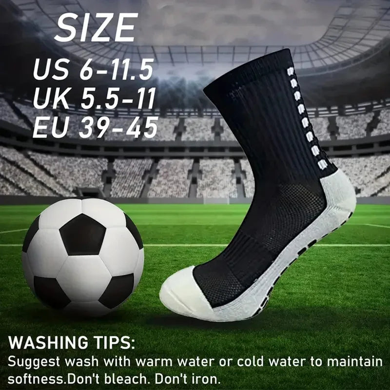 Schwarze rutschfeste Sportsocken neben einem Fußball auf einem grünen Feld.