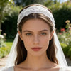 Retrato de cerca de una mujer vistiendo una elegante diadema de encaje floral blanca y velo al aire libre.