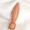 A wooden massage stick with brass accents, featuring a tapered body and decorative ends.