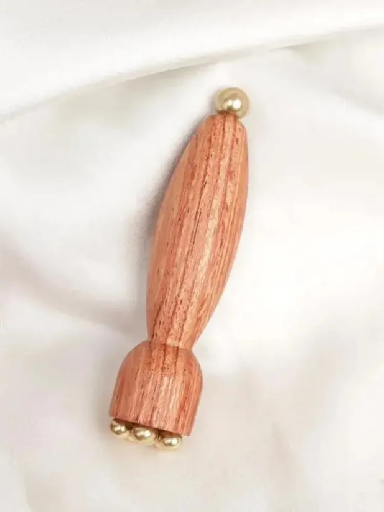A wooden massage stick with brass accents, featuring a tapered body and decorative ends.