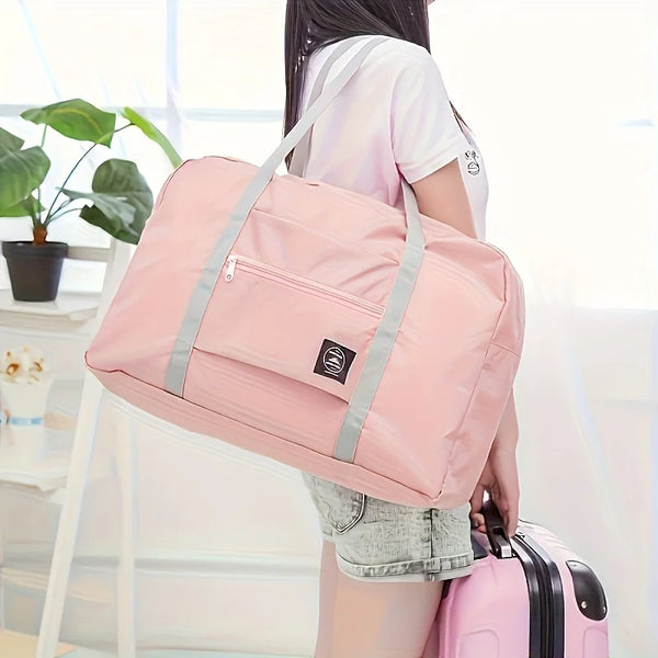 A person is holding a pink foldable travel duffel bag in a bright indoor setting.