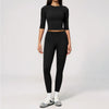 A woman wearing a black long-sleeved top and matching black leggings set for yoga and fitness.