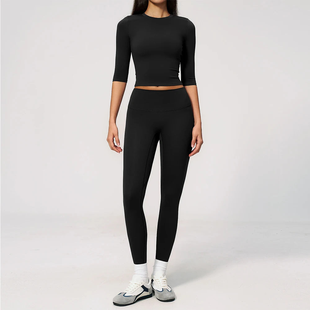 A woman wearing a black long-sleeved top and matching black leggings set for yoga and fitness.