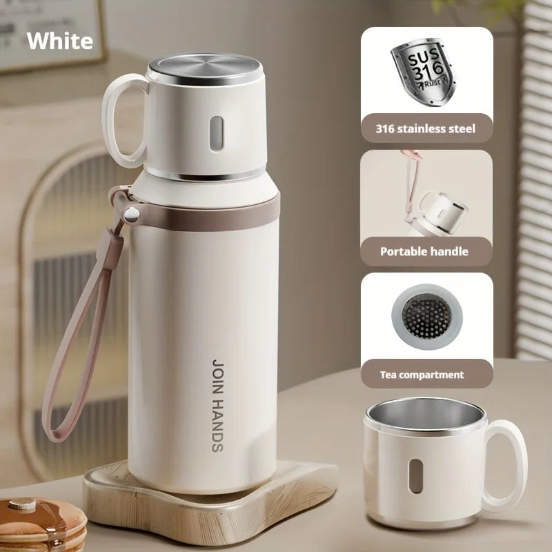 A white 316 stainless steel insulated water bottle with a portable handle and tea compartment is shown on a wooden coaster.