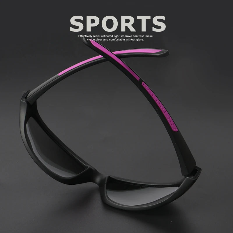 A pair of black sports sunglasses with a pink accent line displayed against a dark background.