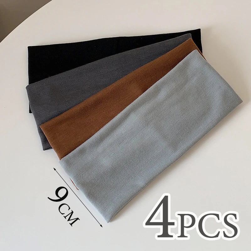 Four gray and brown elastic hairbands laid diagonally on a white surface.