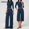 A woman models a navy blue yoga and fitness leggings set consisting of a long-sleeved top and high-waisted pants.