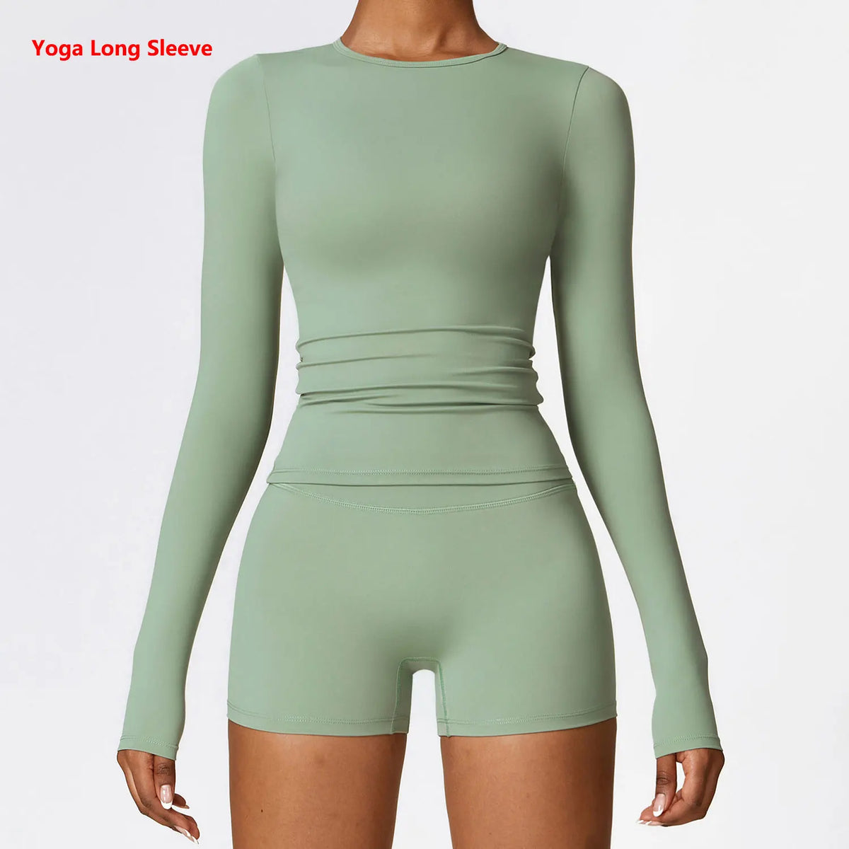 A model wearing a long sleeve sage green yoga and fitness t-shirt with a ruched midsection.