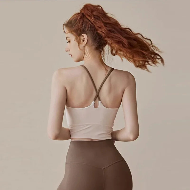 A woman wearing a beige supportive sports bra and matching leggings, with her hair pulled back in an updo.