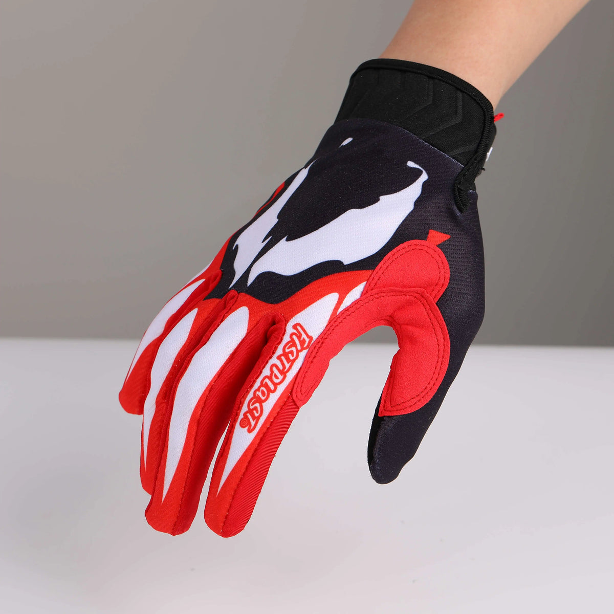 A close-up of red and black cycling riding gloves worn on a hand.
