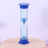 A tall blue hourglass with a clear glass body and a blue lid, resting on a wooden surface.