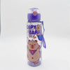 A clear water bottle with a purple lid and a sticker design featuring a bear and the text CAPY BARA.