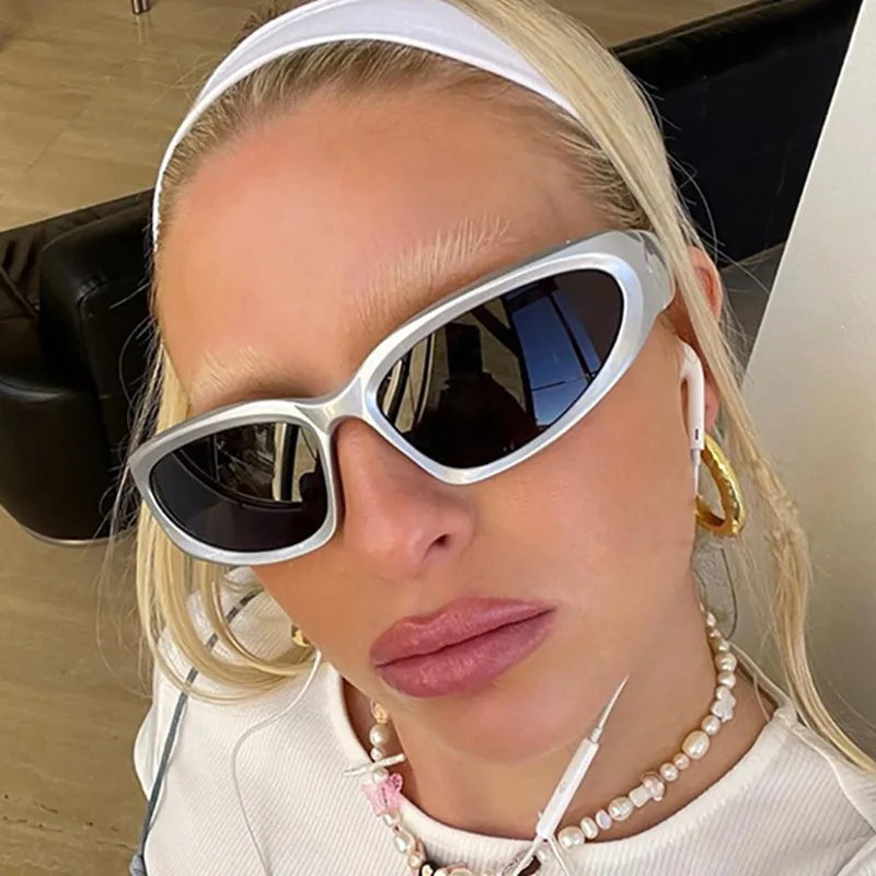 Close-up of a woman wearing silver-framed Y2K retro sports sunglasses and a white top.