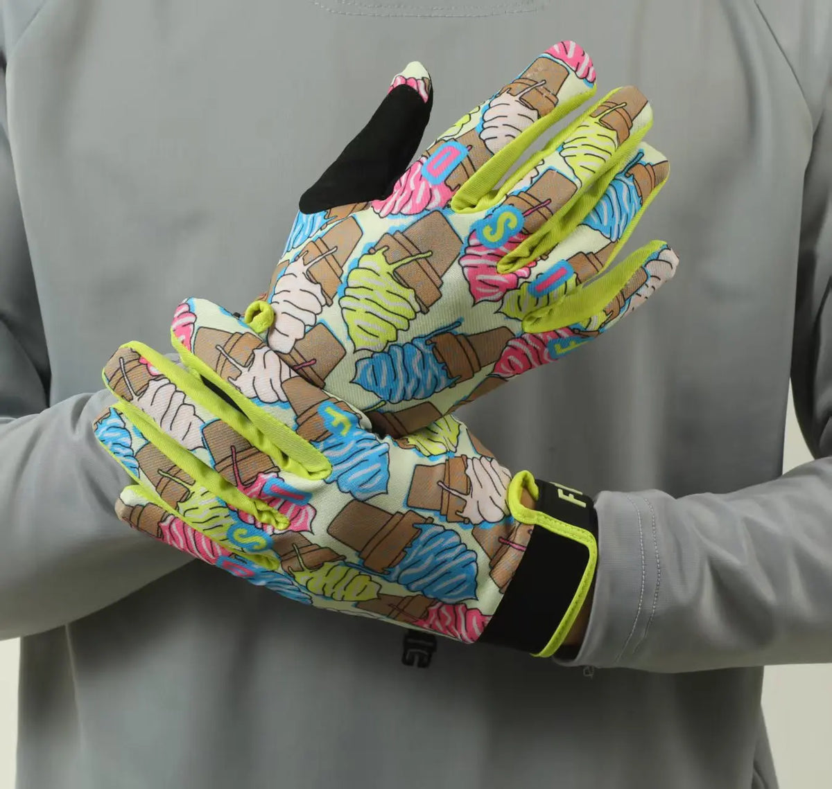 Une paire de gants de motocross colorés pour tout-terrain portés sur la main d'une personne.